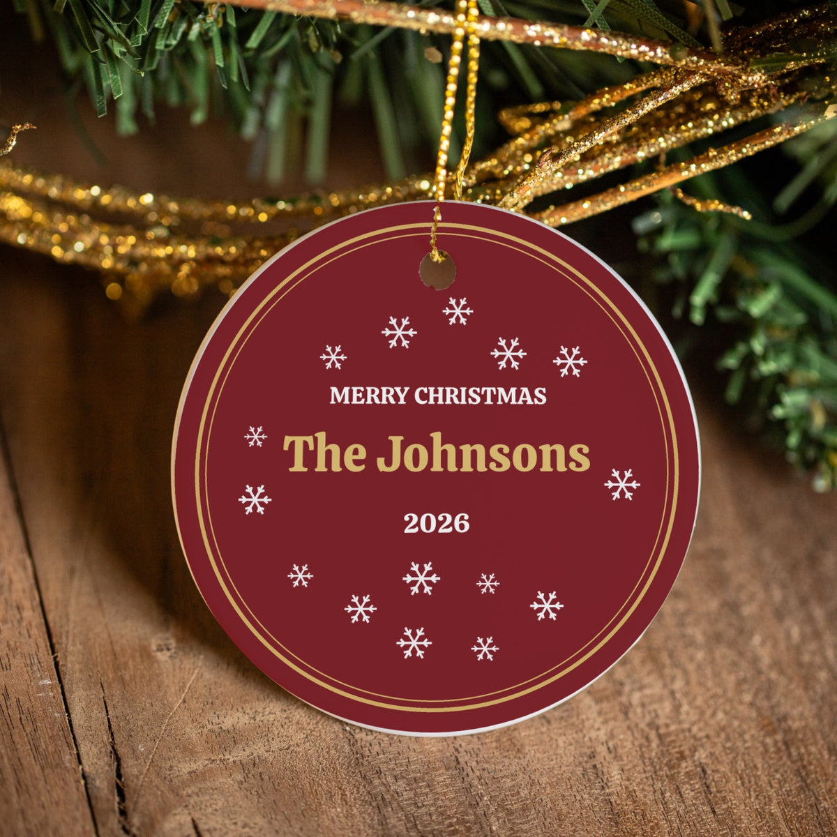 Close-up of the Merry Christmas family name ornament with gold string on a tree