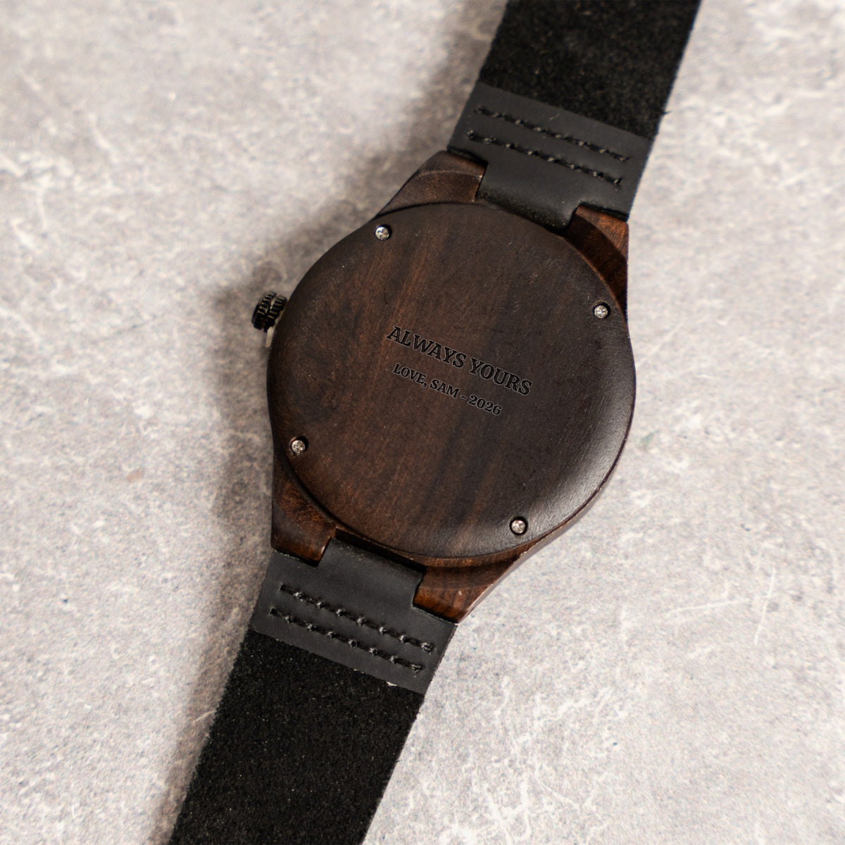 Engraved case back of the personalized wood watch on a marble surface