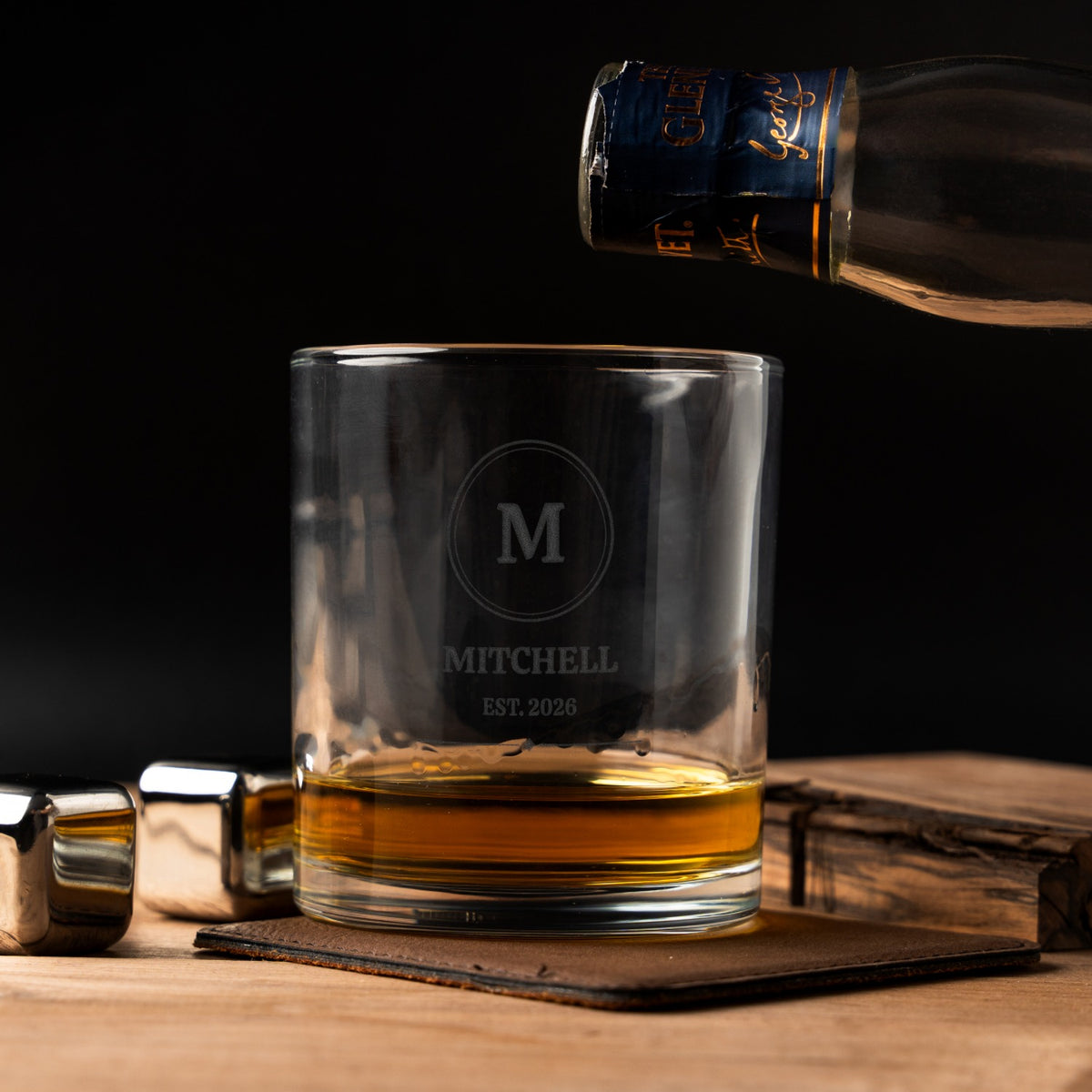 Personalized whiskey rocks glass etched with monogram M, MITCHELL and EST. 2026, being filled with whiskey