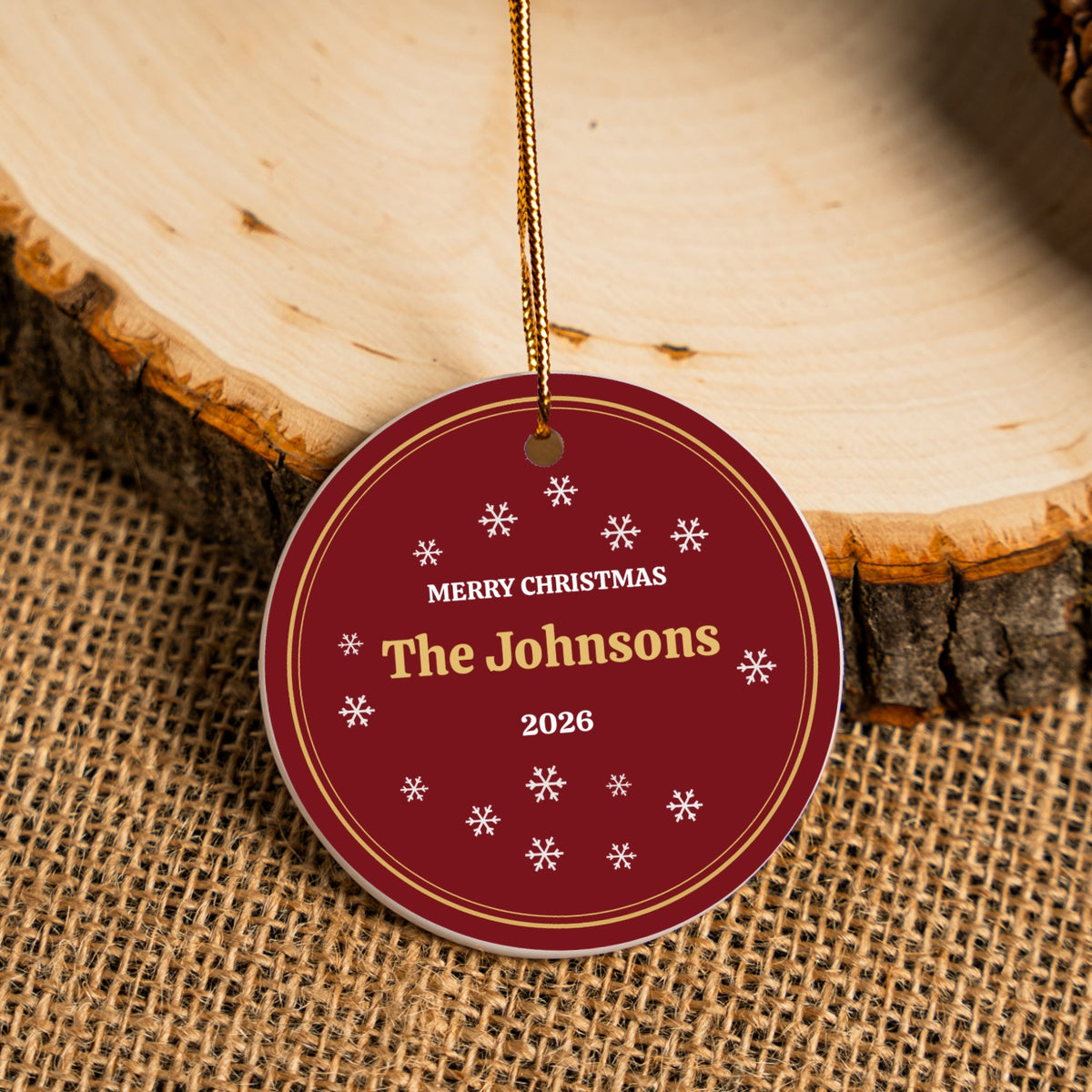 Custom red ceramic Christmas ornament hanging against a wood slice and burlap
