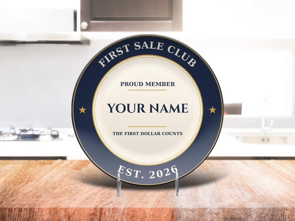 First Sale Club custom name plate standing on a wooden table in a bright kitchen, navy rim with gold stars