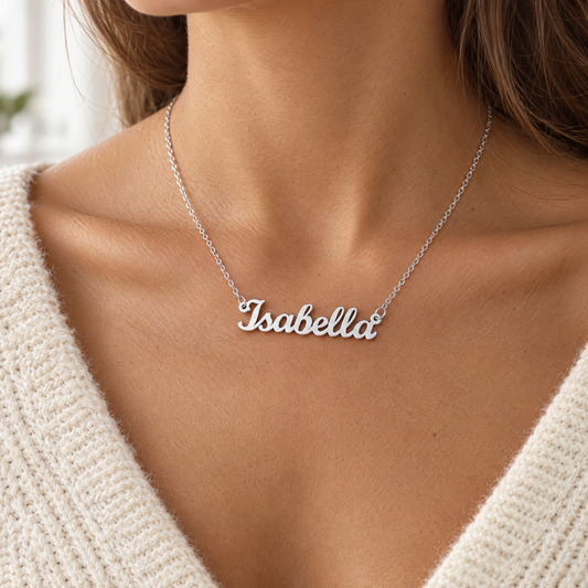 Woman wearing a silver cursive custom name necklace reading Isabella, cream knit sweater