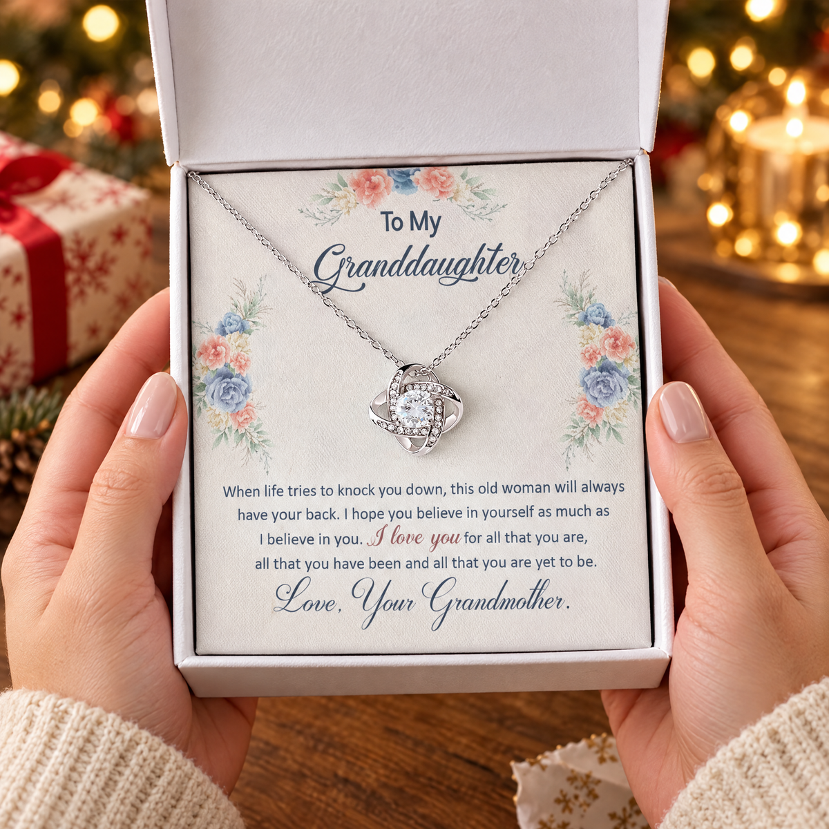 Gift box with the Love Knot necklace and its printed message card, held in two hands