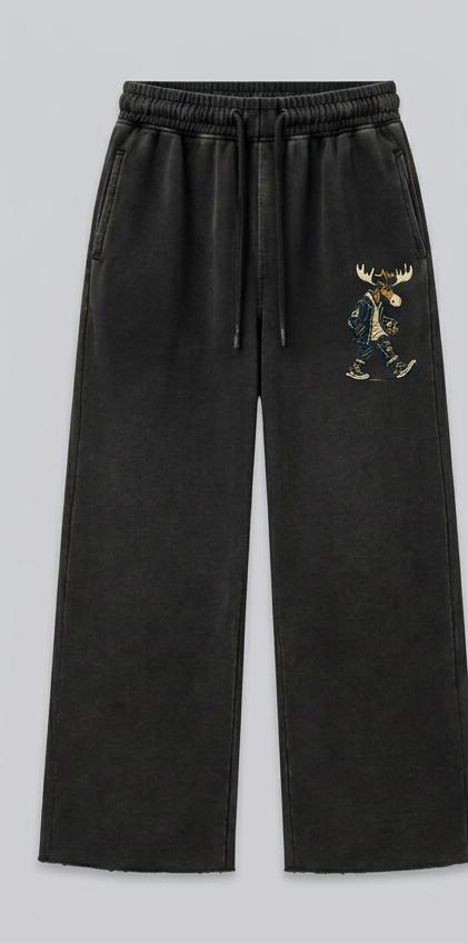 Washed-black drawstring fleece sweatpants, front view, with raw-edge hems and a small cream-and-brass radio-carrying Night Shift Chester on the thigh; design mockup.