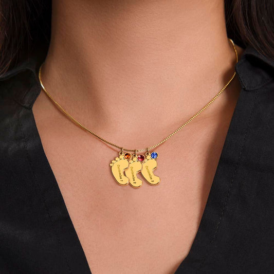 Woman wearing the gold engraved baby feet necklace with three name-engraved feet charms and birthstones, a personalized gift for mom